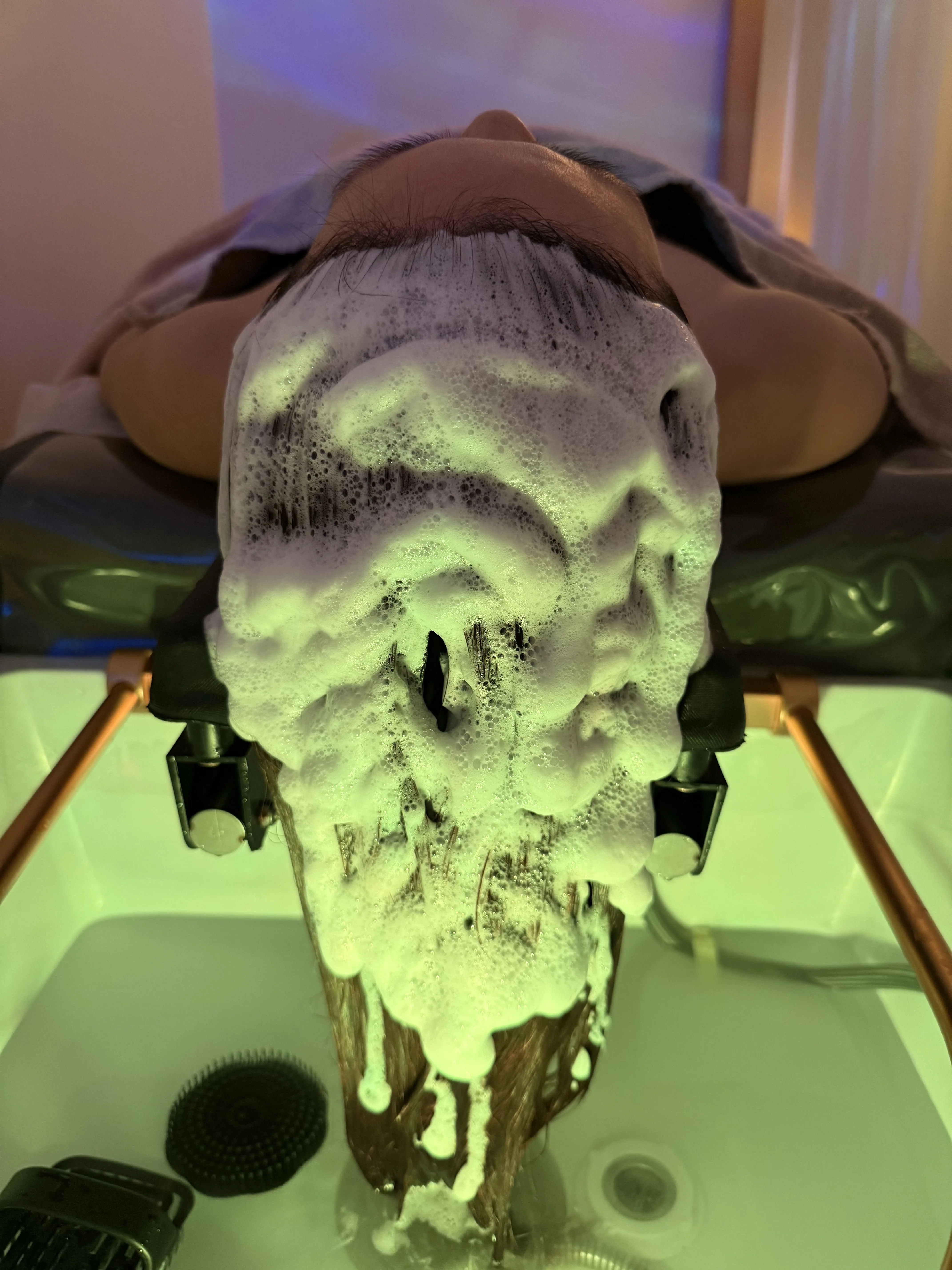 Cleansing foam cascading into the halo basin, soft green ambient light