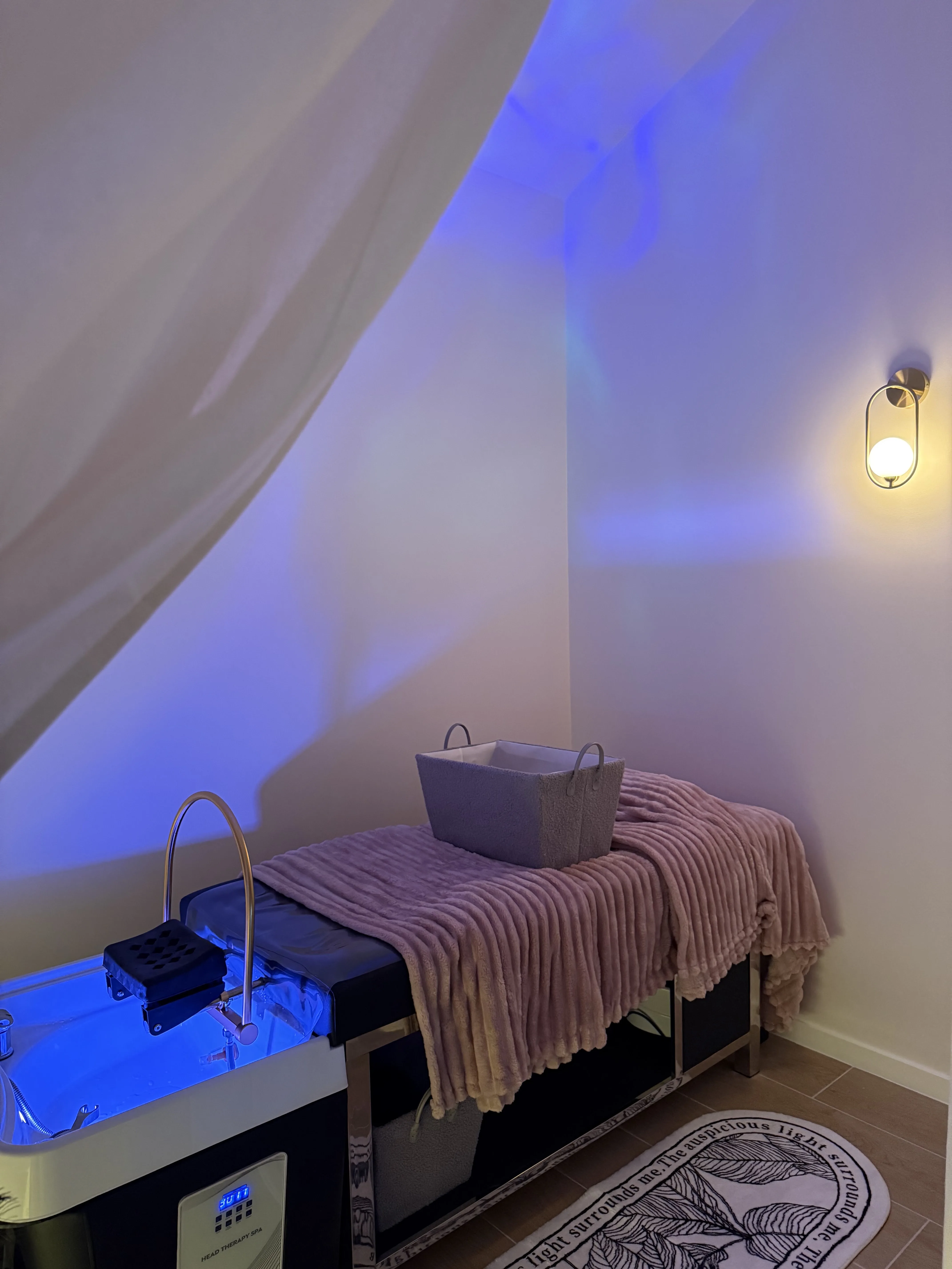 Blue-lit treatment room with the water-halo basin and blush throw